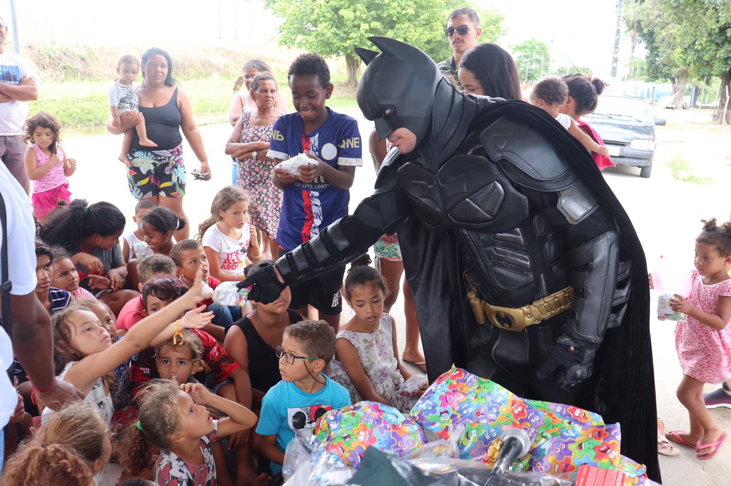 Batman Thyago distribuindo presentes para crianças em uma comunidade