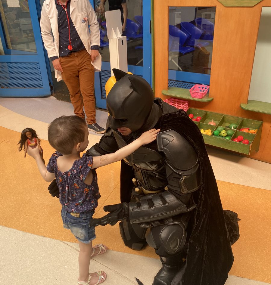 Criança tocando a armadura do Batman na brinquedoteca do hospital